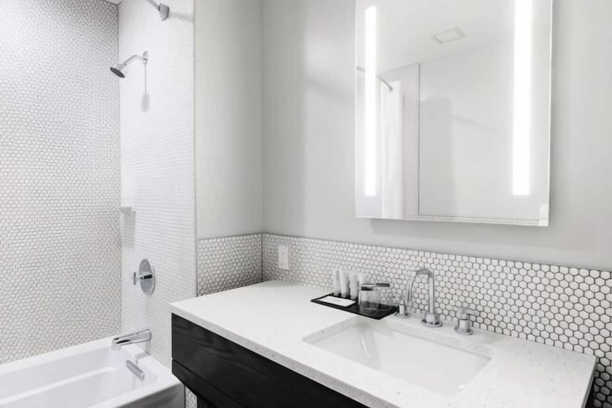 A modern bathroom with a white sink, mirror, and shower.