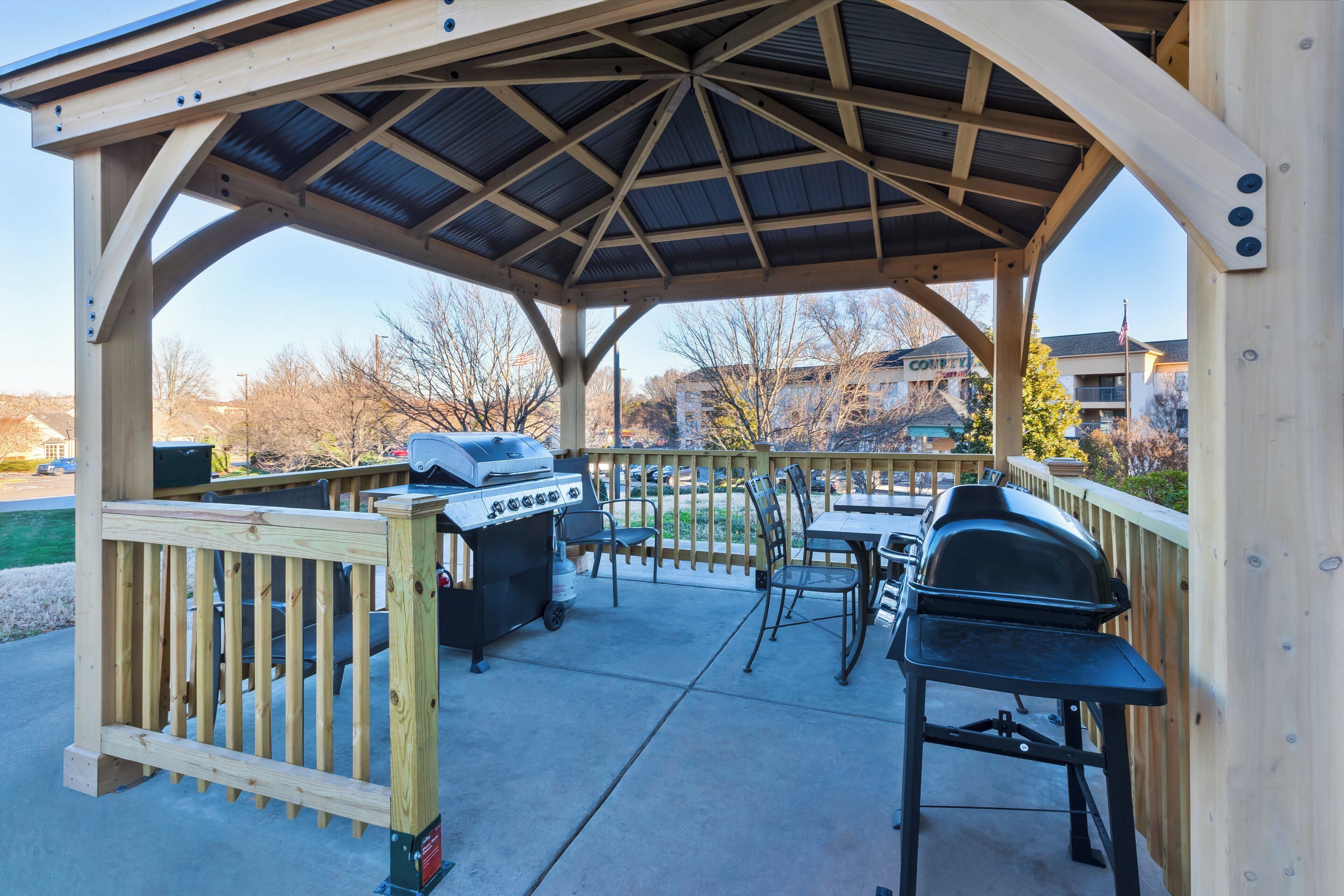 A covered outdoor patio with a grill and seating area.