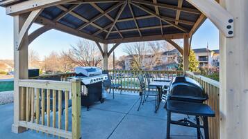 A covered outdoor patio with a grill and seating area.