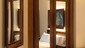 Una camera d'albergo con un letto grande, un armadio in legno, uno specchio e un comodino.
