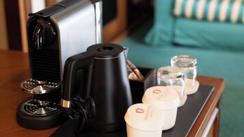 Ein Hotelzimmer mit einer Kaffeemaschine, einem Wasserkocher und drei Gläsern auf einem Holztisch.