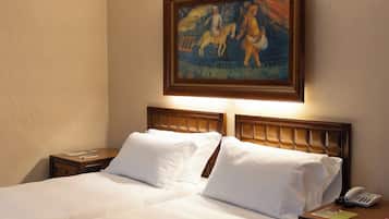 Ein Hotelzimmer mit einem großen Bett, einem Holz-Kopfteil, Nachttischen, einem Bild an der Wand und einem blauen Teppich mit Muster.