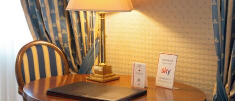 Ein Hotelzimmer mit einem runden Holztisch, einer Lampe, einem Stuhl, einem Schild, das auf eine Kamera in dem Raum hinweist, und einer Wand mit Muster.