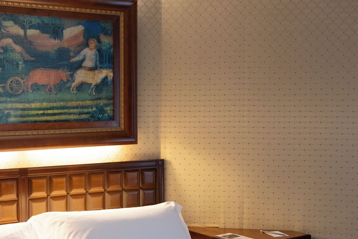 Habitación de hotel con cama, mesita de noche y un cuadro en la pared.