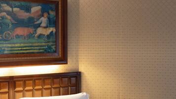 Een hotelkamer met een bed, nachtkastje en een schilderij aan de muur.