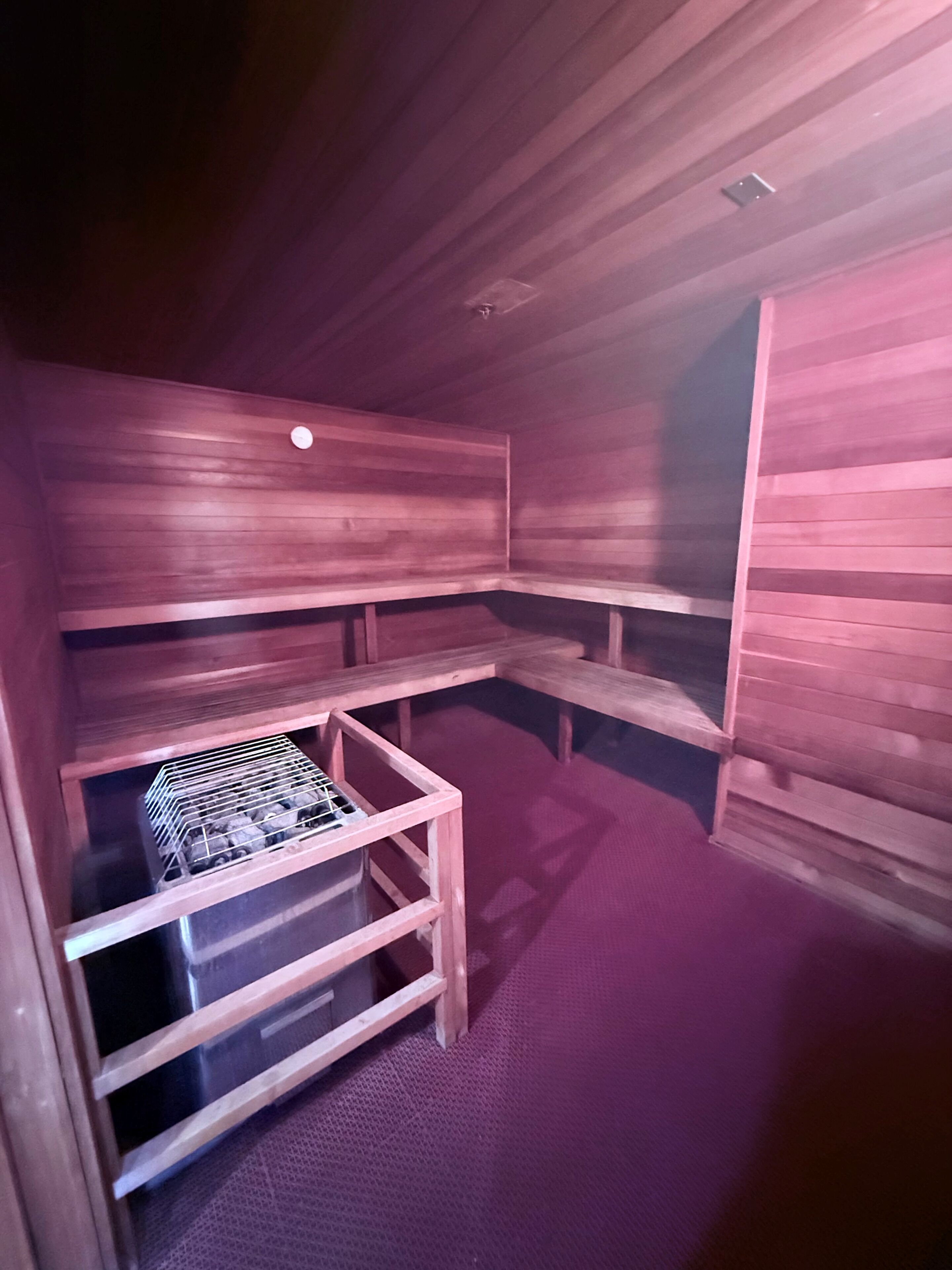 Un sauna avec des bancs en bois et une étagère en métal.