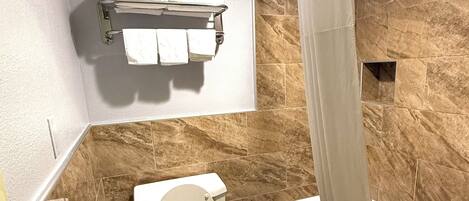 Une salle de bain comprenant des toilettes, une douche avec un rideau et un porte-serviettes avec des serviettes.