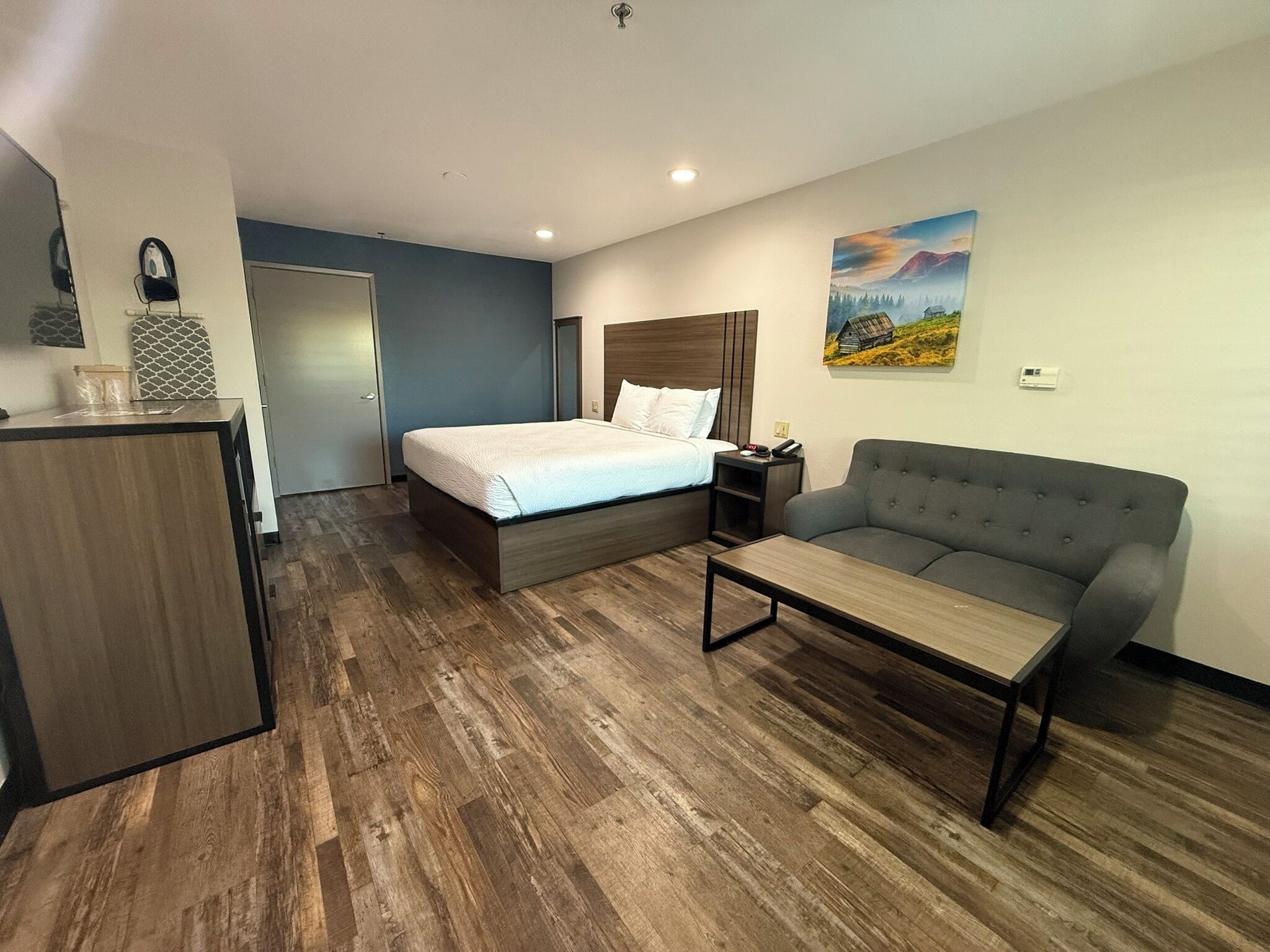 Een hotelkamer met een bed, een bank, een bureau en een schilderij aan de muur.