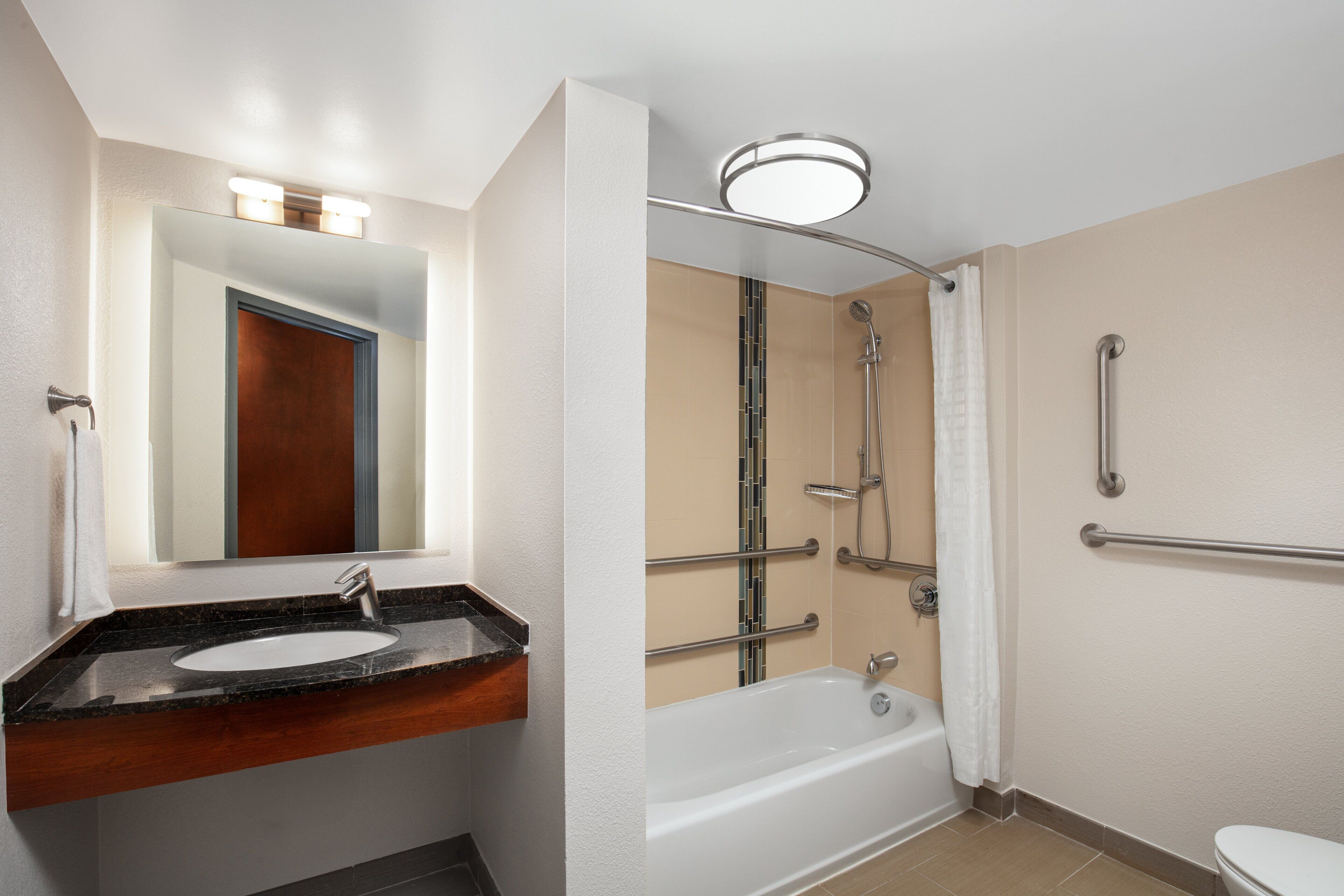 Une salle de bain moderne équipée d’un lavabo, d’un miroir, d’une douche et de toilettes.