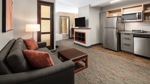 A modern hotel room with a sofa, a flat-screen TV, a kitchenette, and a bathroom visible through an open door. - Candlewood Suites Birmingham - Inverness by IHG (Birmingham)