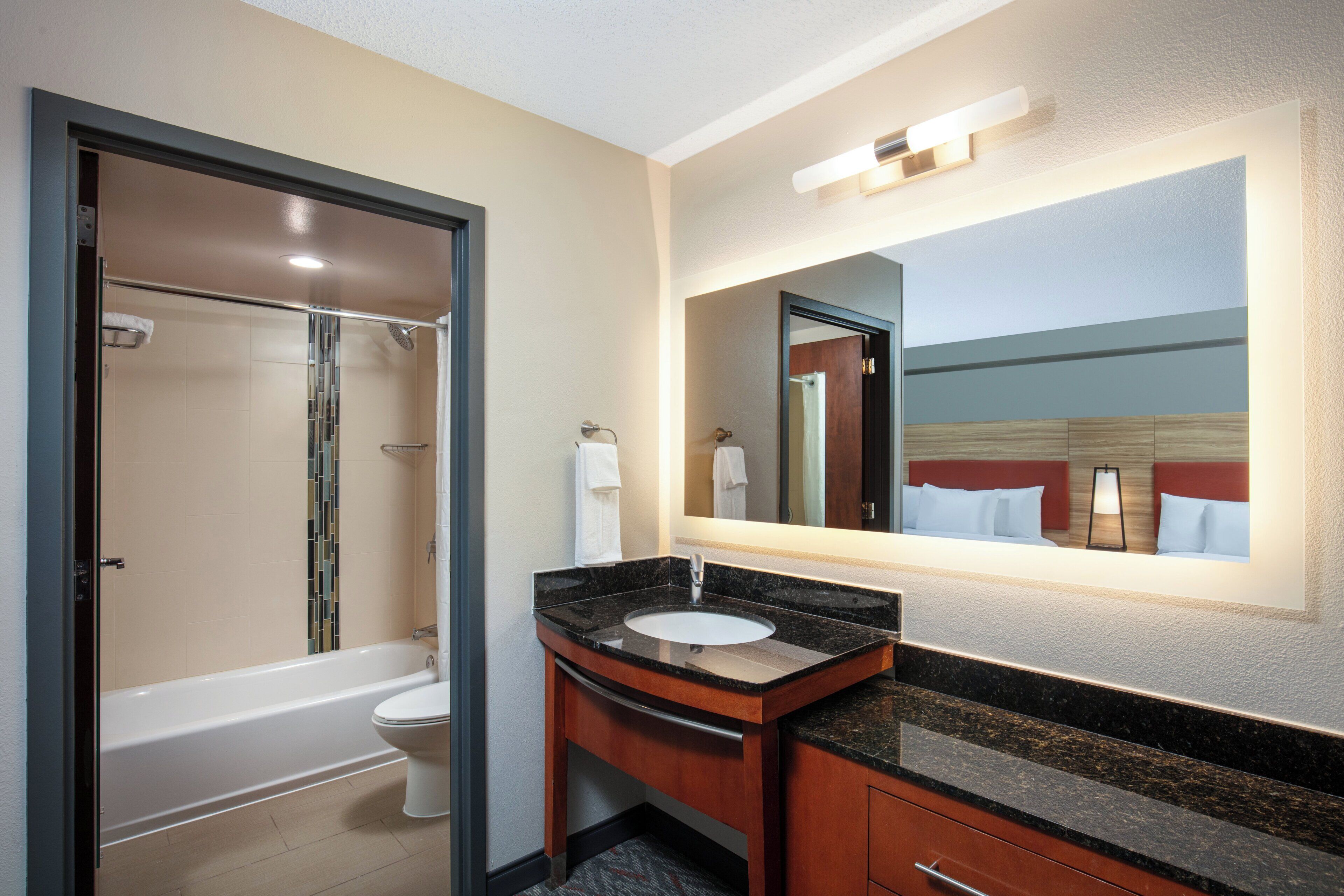 Un baño de hotel con bañera, inodoro y tocador con lavabo.
