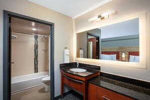A modern bathroom with a bathtub, toilet, and vanity with a sink and mirror. - Candlewood Suites Birmingham - Inverness by IHG (Birmingham)