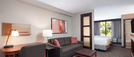 Une chambre d’hôtel équipée d’un bureau, d’un fauteuil de bureau, d’un canapé et d’un lit.