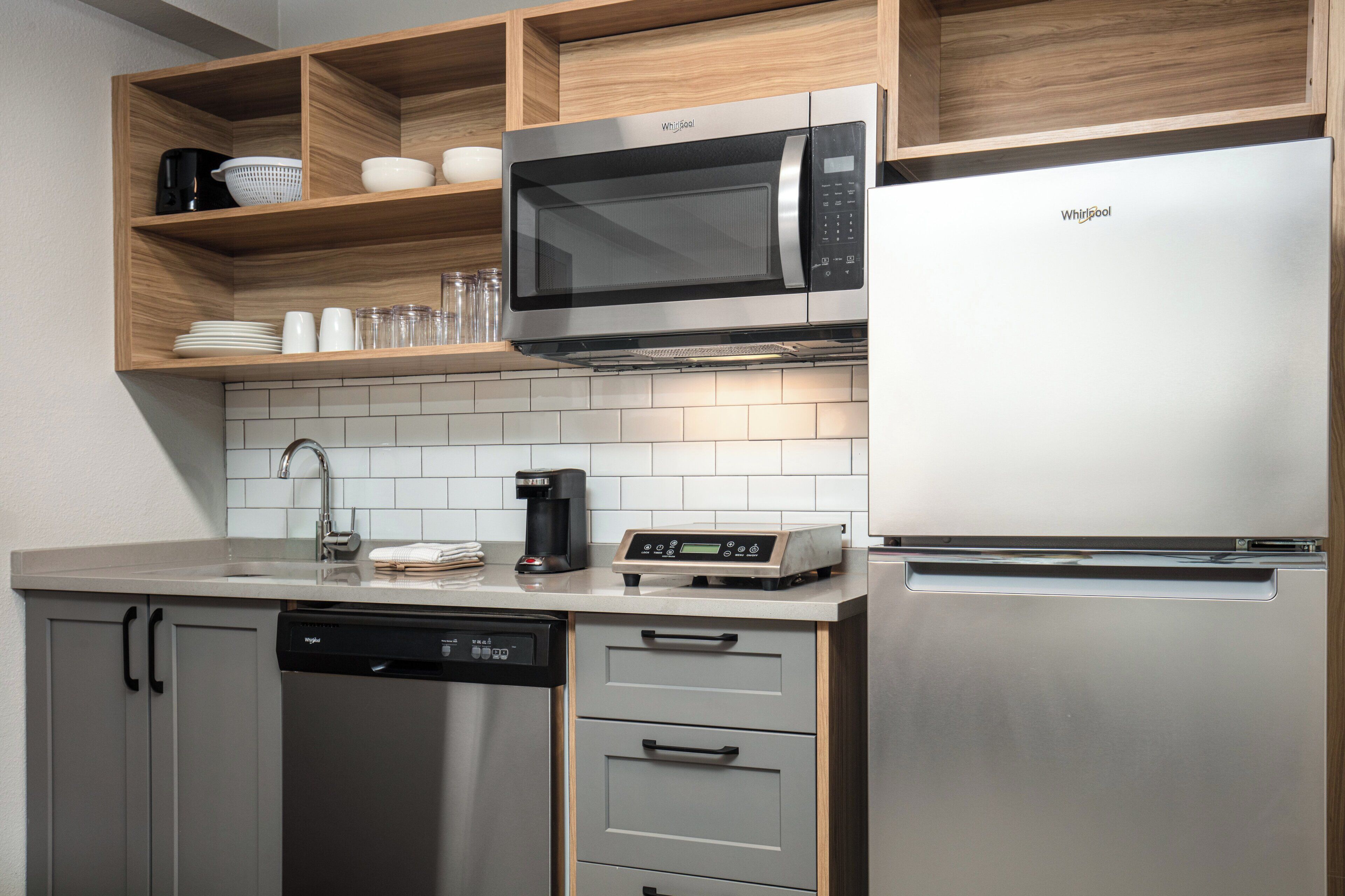 Una cocina moderna con microondas integrado, cafetera y lavavajillas.