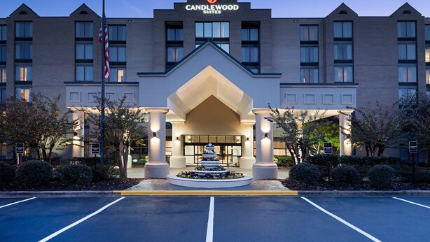 A hotel entrance with a modern design, featuring a prominent sign, a landscaped entrance, and a parking area. - Candlewood Suites Birmingham - Inverness by IHG (Birmingham)