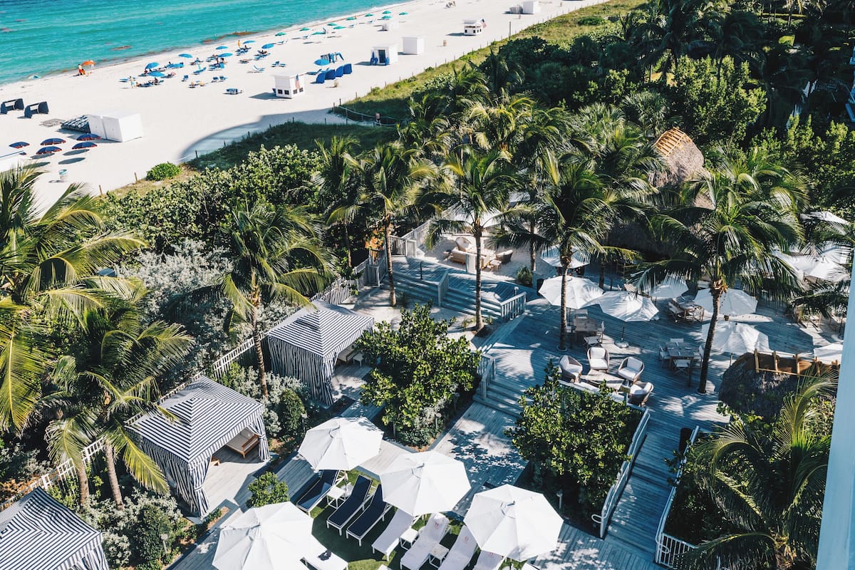 A resort with a pool, beach, and palm trees.