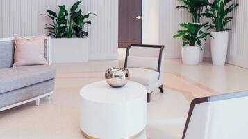 A modern living room with a grey sofa, a white armchair, a round coffee table, and potted plants.