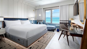 A modern hotel room with a large bed, a desk with a chair, a TV, and a view of the sea. - Cadillac Hotel & Beach Club, Autograph Collection (Miami Beach)