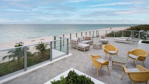 A balcony with wicker furniture overlooking a beach. - Cadillac Hotel & Beach Club, Autograph Collection (Miami Beach)