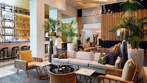 A modern hotel lobby with a bar area, seating arrangements, and large potted plants. - Cadillac Hotel & Beach Club, Autograph Collection (Miami Beach)