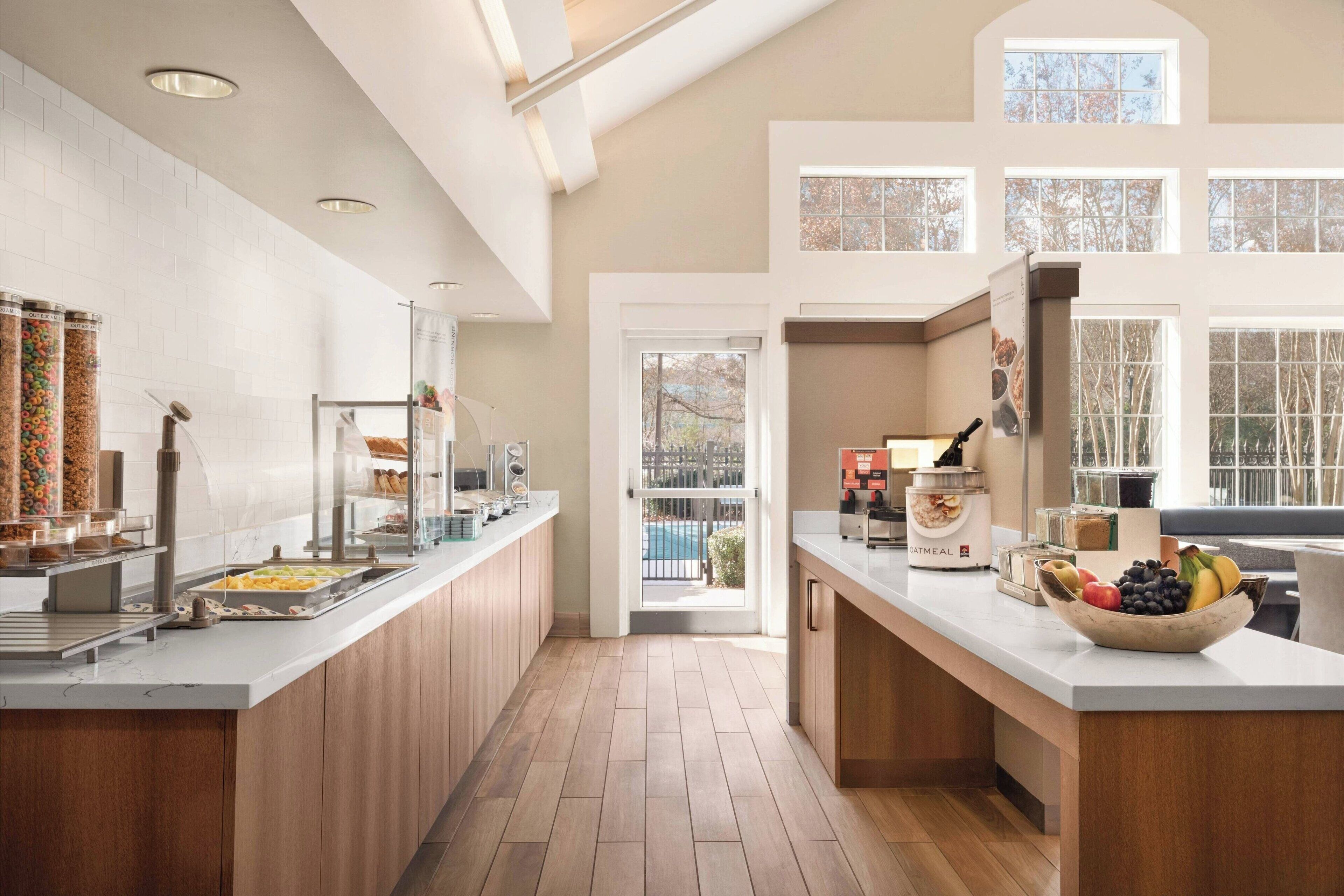 A modern kitchen with a breakfast bar, a view of the outdoor pool, and a large window.