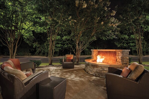An outdoor seating area with wicker furniture and a stone fire pit. - Residence Inn by Marriott Atlanta Duluth/Gwinnett Place (Duluth)