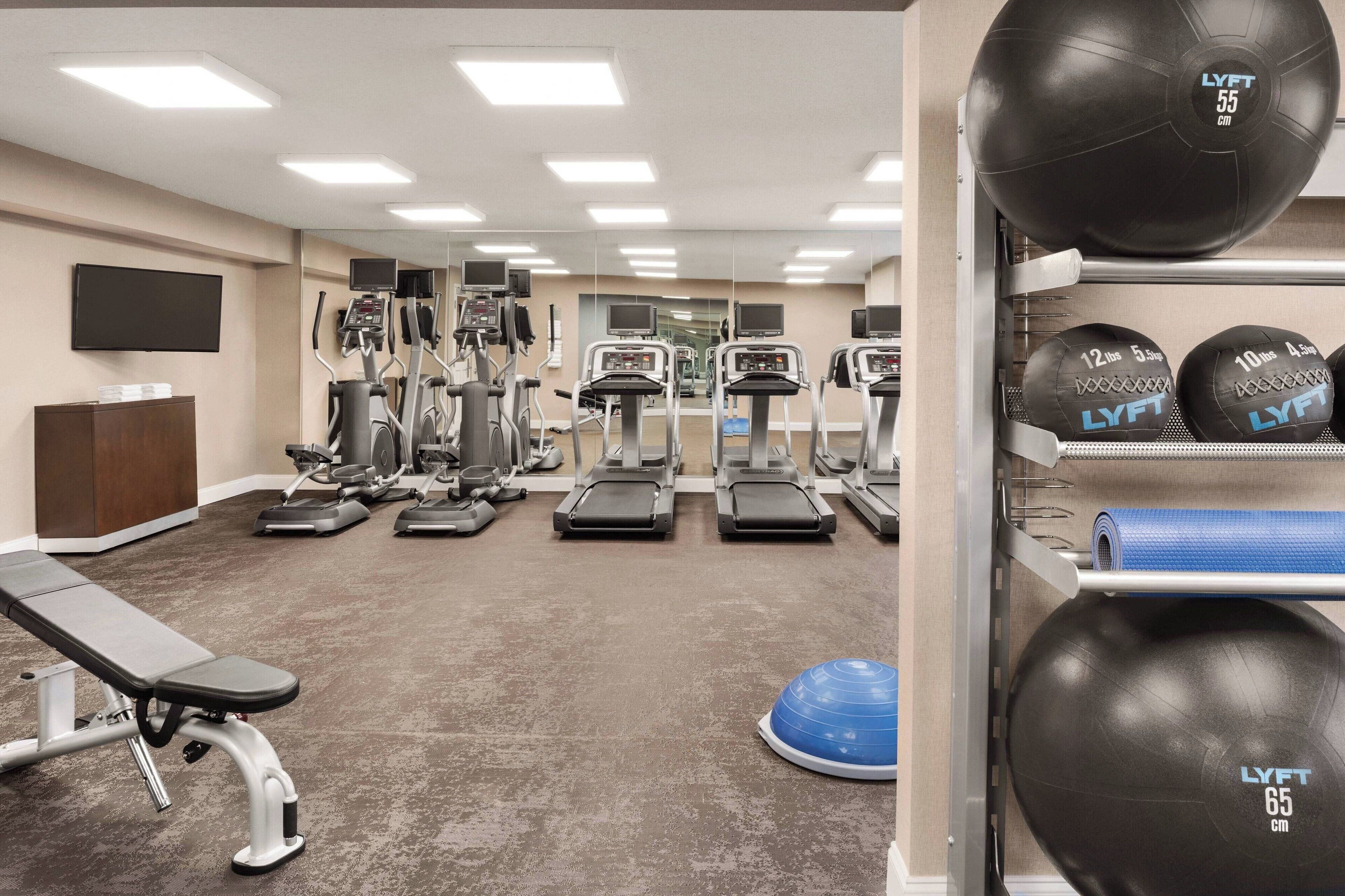 Uma academia com esteiras, elípticos e equipamentos de musculação.