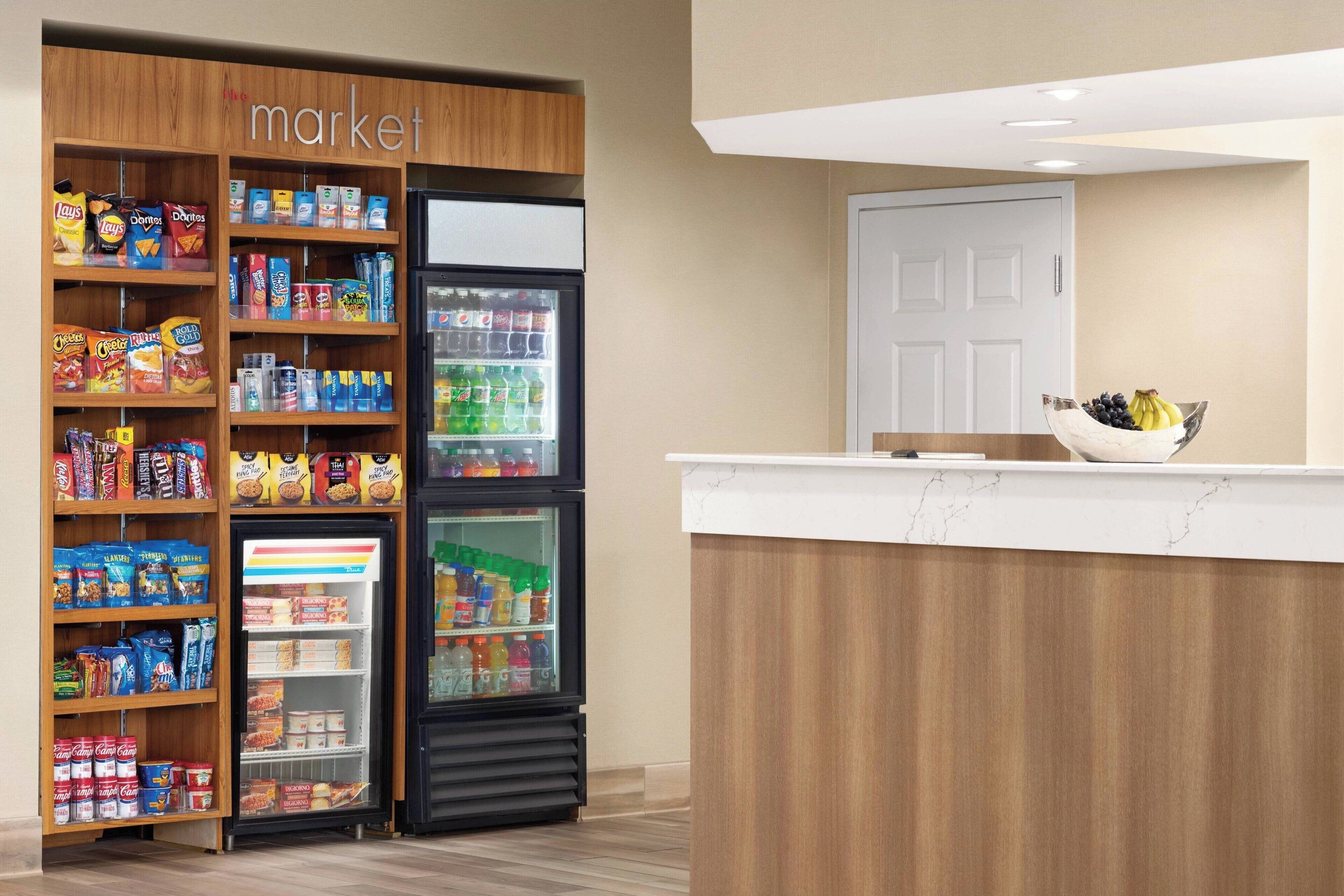 A hotel reception area with a wooden reception desk, a fruit bowl, and a snack vending machine.