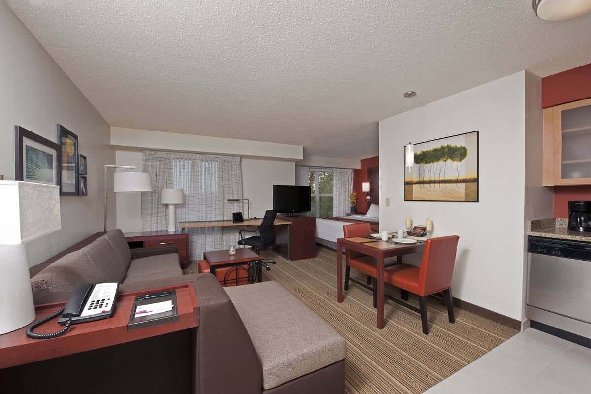 Ein kompaktes Hotelzimmer mit Wohnbereich, Küchenzeile und Essbereich.