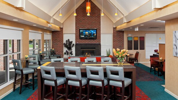 A modern bar area with a brick fireplace, large TV, and comfortable seating. - Residence Inn Lansing West (Lansing)