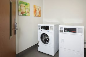 A laundry room with two front-loading washing machines and two dryers. - Fairfield Inn & Suites by Marriott® Grand Rapids Airport (Grand Rapids)