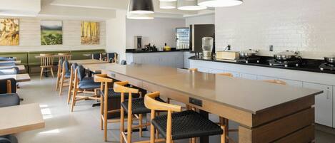 A modern kitchen with a central island, bar stools, and pendant lighting.