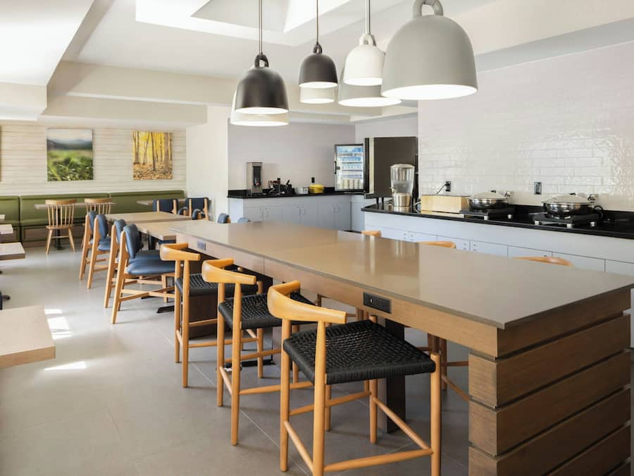 Una cocina moderna con una isla central, taburetes de bar e iluminación colgante.