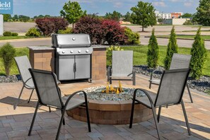 An outdoor patio with a grill, fire pit, and seating area. - Fairfield Inn & Suites Saginaw (Saginaw)