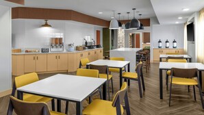 A modern dining area with yellow chairs and white tables, wooden cabinets, and pendant lighting. - Fairfield Inn & Suites Saginaw (Saginaw)