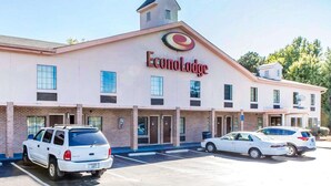 Un edificio de EconLodge de dos pisos con entrada central, estacionamiento y una estructura pequeña similar a una torre en el techo.