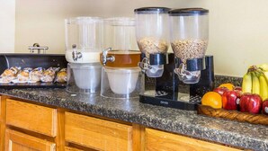 Una encimera de cocina con una cafetera, un dispensador de pan y un frutero.