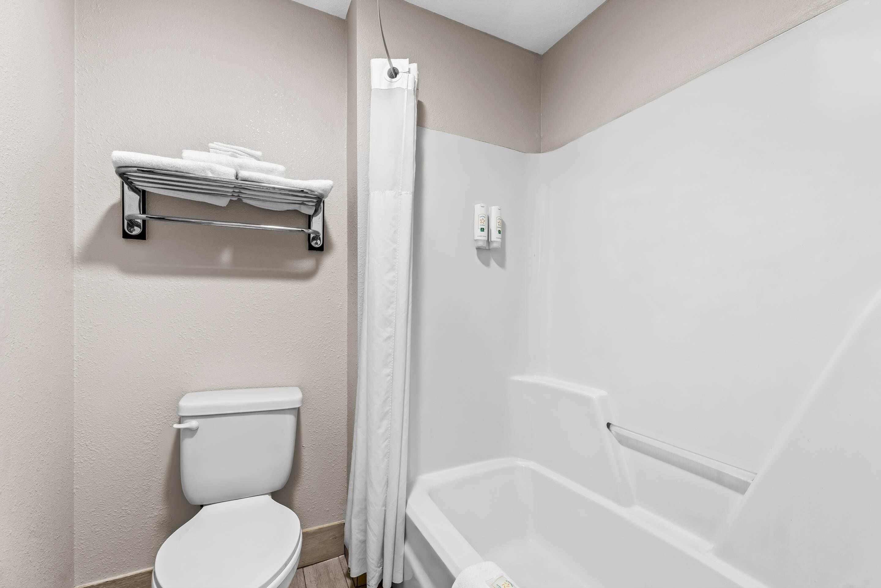 Un baño con inodoro, ducha con cortina y toallero.