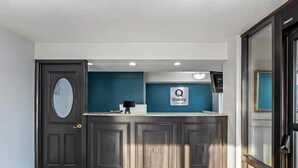 A reception area with a dark wooden counter, a blue accent wall, and a sign that reads "Quality by Ochoa Hotel". - Quality Inn Richland - Jackson South (Richland)