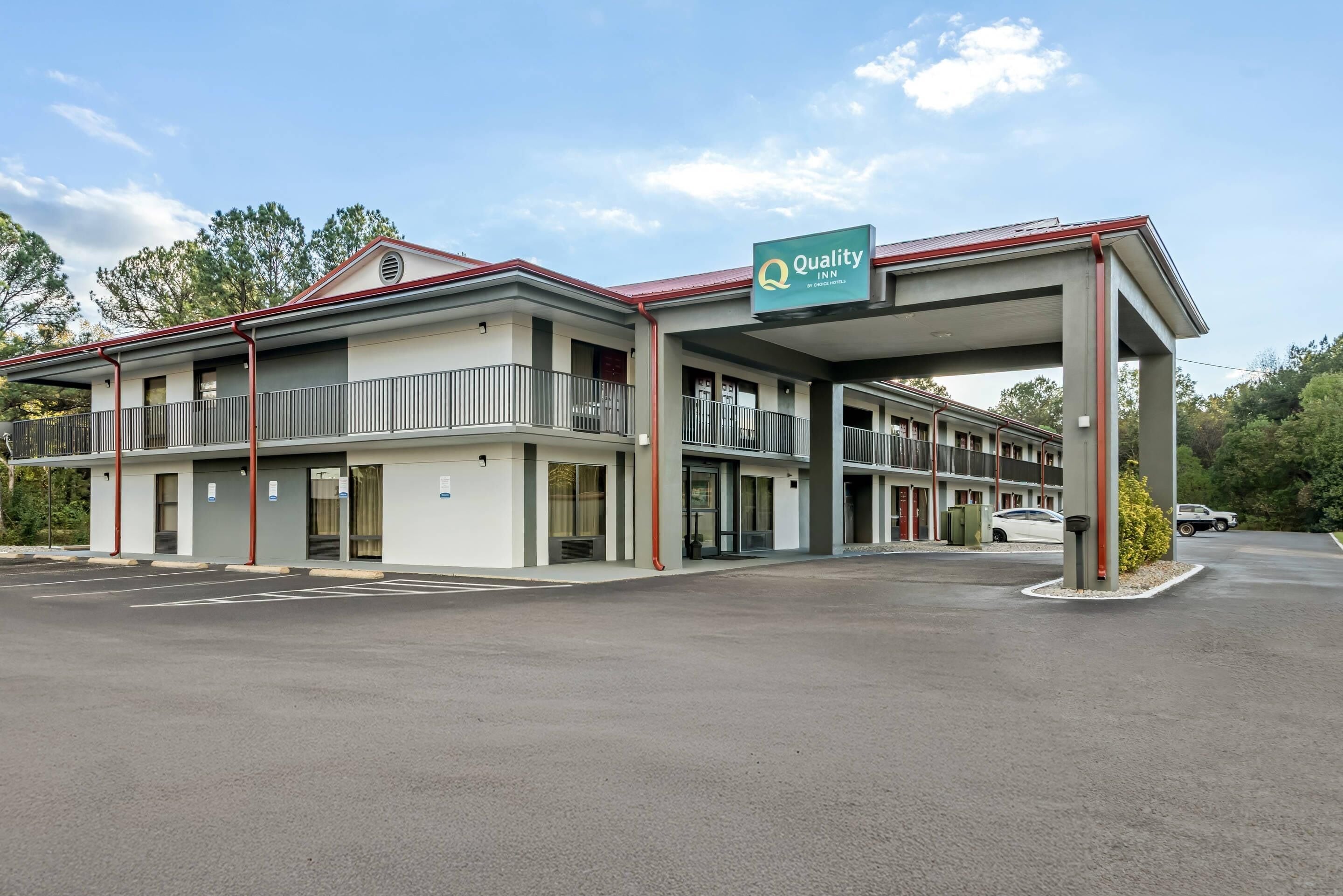 A motel with a covered parking area, multiple rooms, and a sign indicating it is a Quality Inn by Choice Hotels.