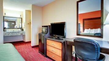 Een hotelkamer met een bed, een bureau met een televisie, een spiegel en een rode tapijtvloer.