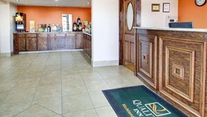 A hotel lobby with a reception desk, a coffee machine, and a kitchen area in the background. - Quality Inn Richland - Jackson South (Richland)