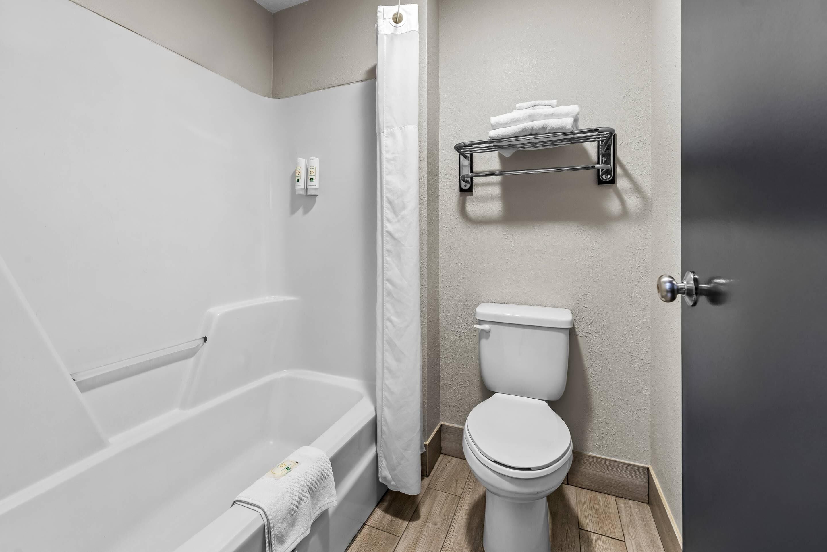 Un baño con bañera, inodoro y un perchero para toallas.