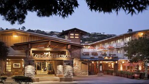 Un hotel con una entrada destacada, fachada de piedra y zona de estar al aire libre.