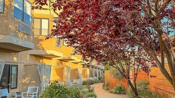 A pathway leading to outdoor seating areas with a building on one side.