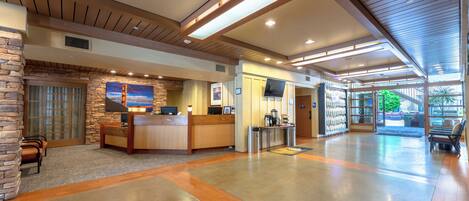 A spacious lobby with a reception desk, seating area, and a large window offering a view of the outdoors.