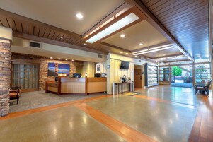 Um hall espaçoso com balcão de recepção, área de estar e uma grande janela com vista para o exterior.