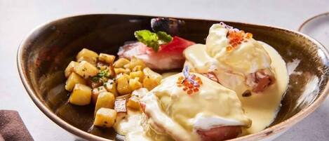 A dish with poached eggs, potatoes, and a red fruit garnish in a ceramic bowl.