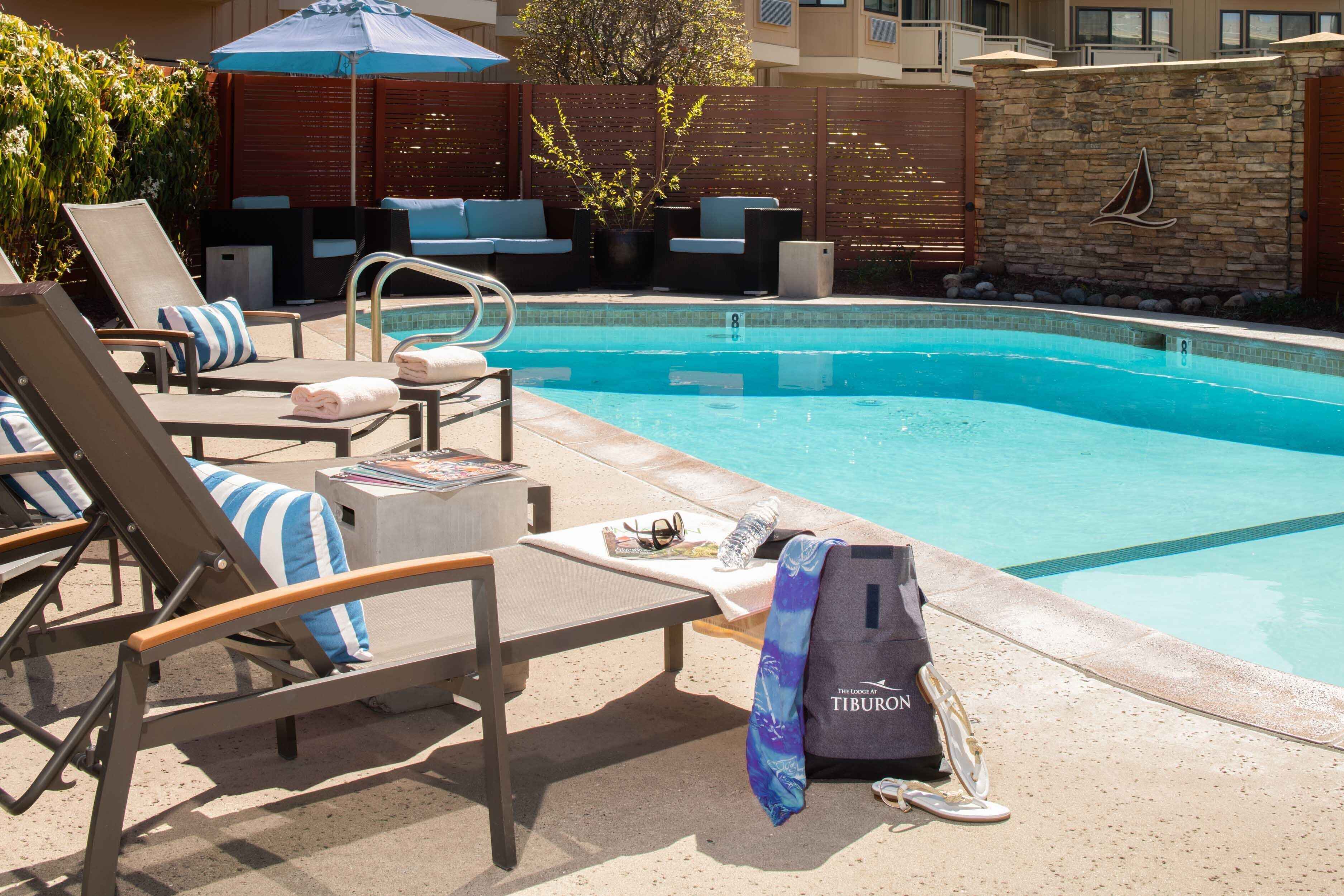 A poolside area with lounge chairs, a small pool, and a stone wall with a logo.