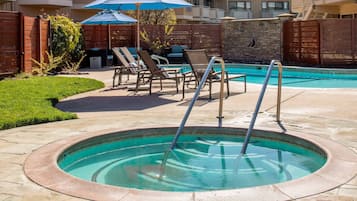 Une piscine bordée de pierres, entourée de chaises longues et de parasols.